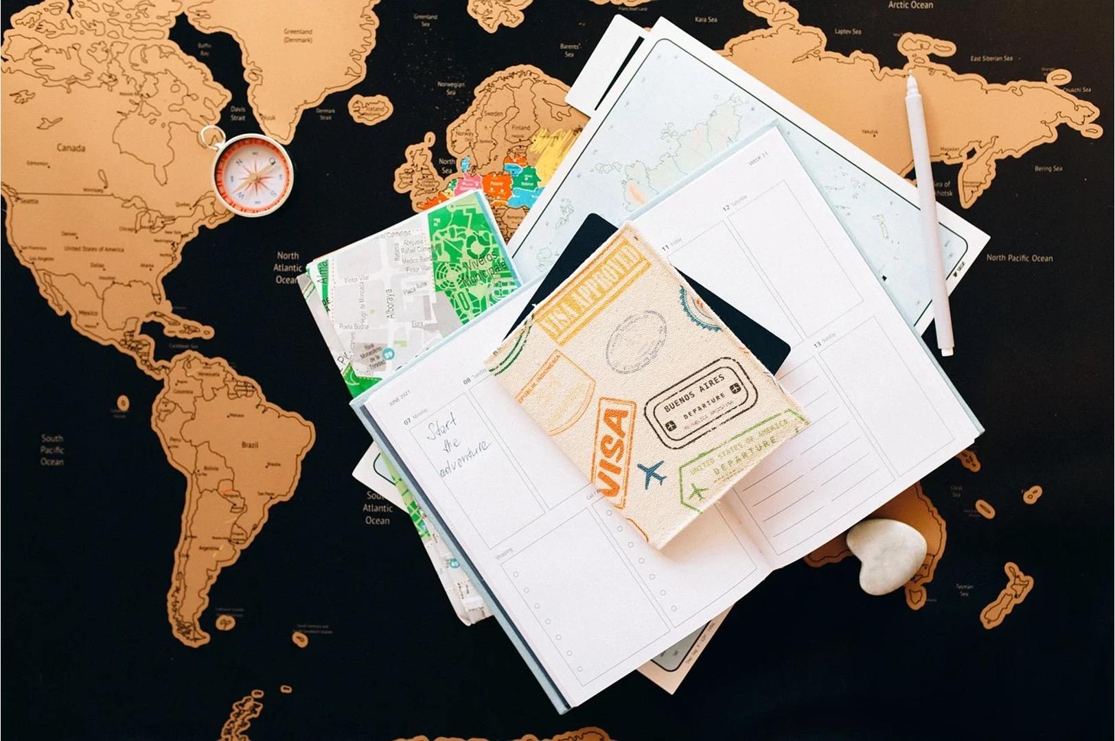 Passport and travel documents on a world map with a compass and a pen